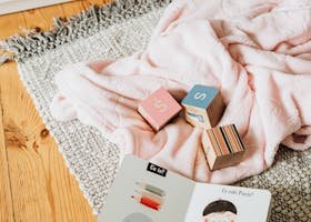 A cozy setup with educational blocks and a children's book on a woven rug.